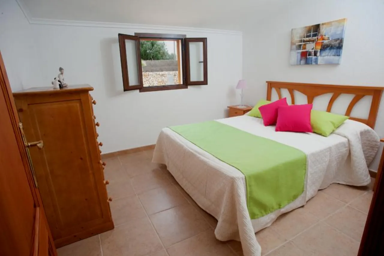 A double bedroom with a shuttered window at Finca Es Torrent den Cosme