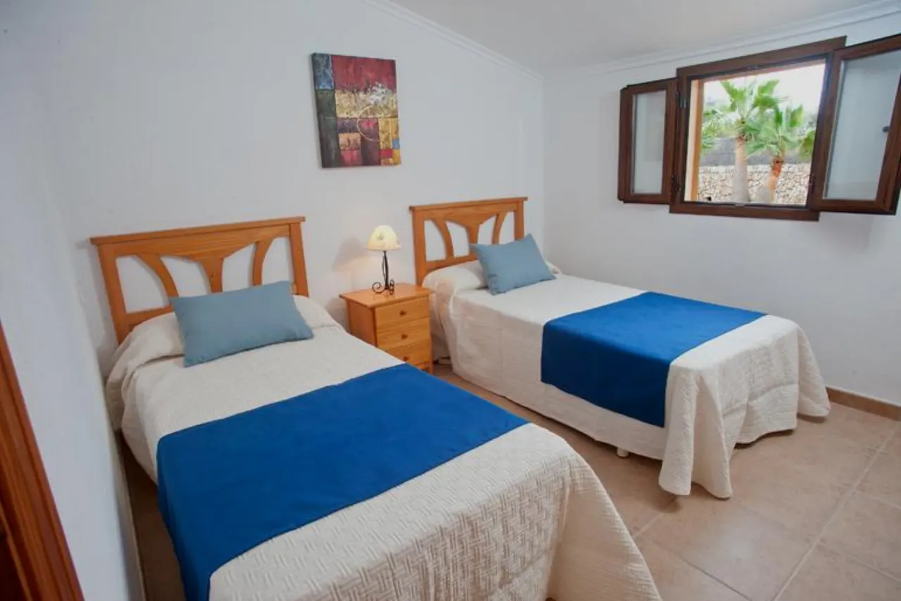A twin bedroom with blue throws and a shuttered window