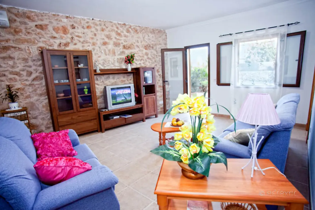 The living room with an exposed dry-stone wall, blue sofas and a fireplace