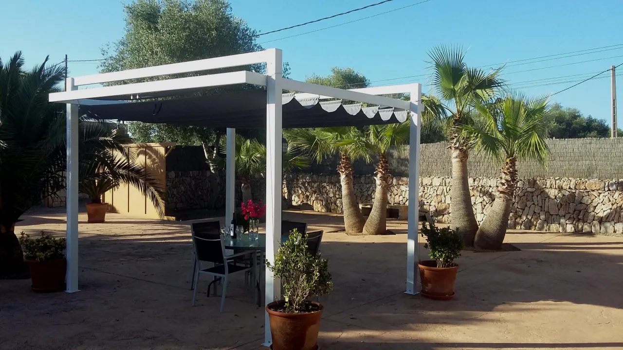 The white pergola and dining table in golden evening light at Finca Es Torrent den Cosme